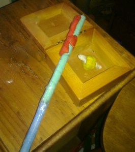Photo of a handmade wand with a golden snitch in a box.